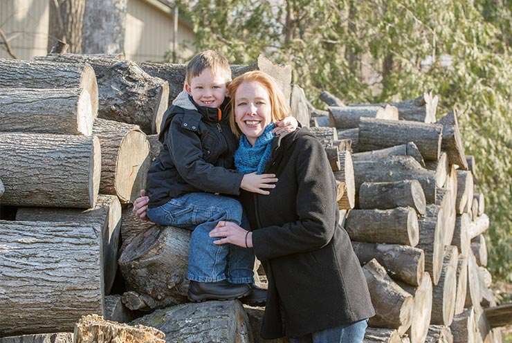 breast cancer patient erika lojko posed on wood pile with her son