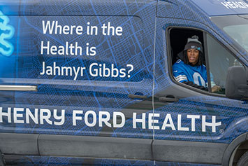 Detroit Lions Running Back Jahmyr Gibbs driving a Henry Ford Health van