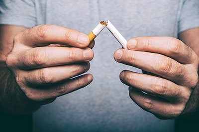 man holding broken cigarette