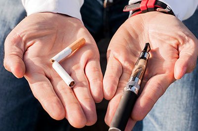 one hand has a broken cigarette and the other a e-cigarette