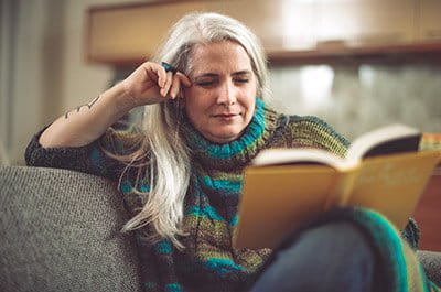 A woman relaxing on a couch reading a book