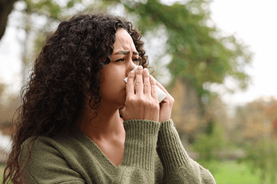 woman blowing nose outside