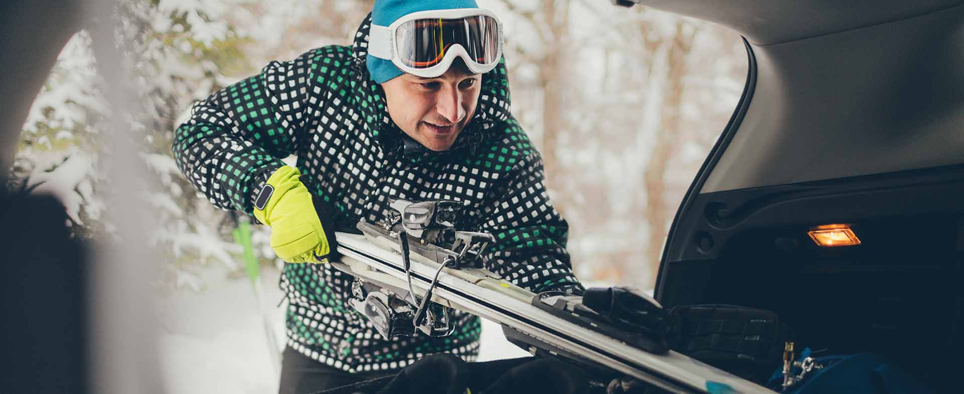 man putting skis in trunk