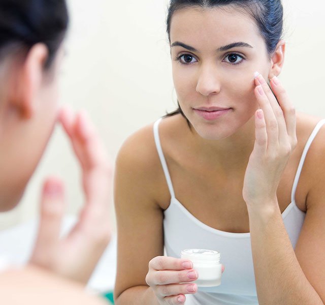 woman putting lotion on face