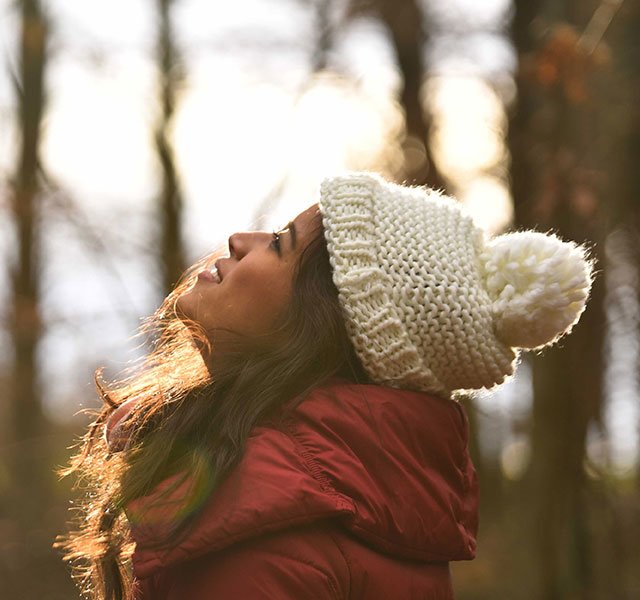 woman with hat standing in the woods
