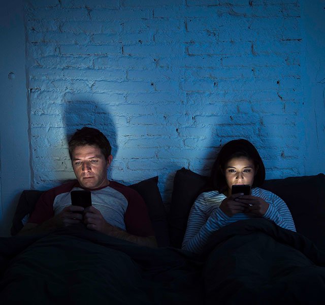 couple in bed on their phones