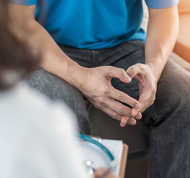 man sitting with hands interlocked