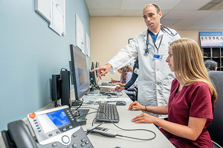 Faculty physician reviews information on a computer screen with a resident physician at Henry Ford Health Seville Family Medicine clinic.