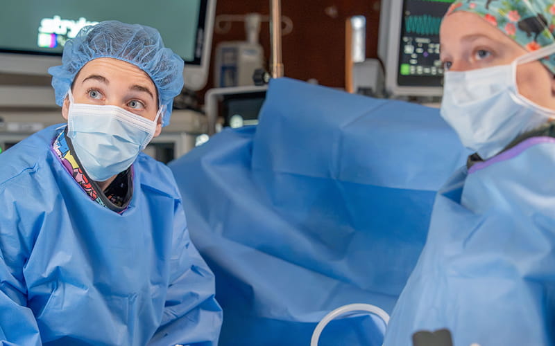Two residents in a surgery room preforming a proccedure.