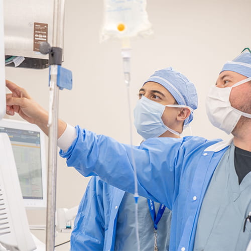 Two residents reviewing the vital monitoring screen of a patient