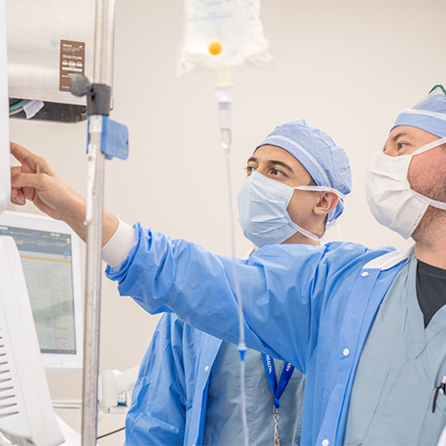 Two residents reviewing the vital monitoring screen of a patient