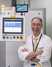 Stephen Brown, PhD standing with radiation cabinet