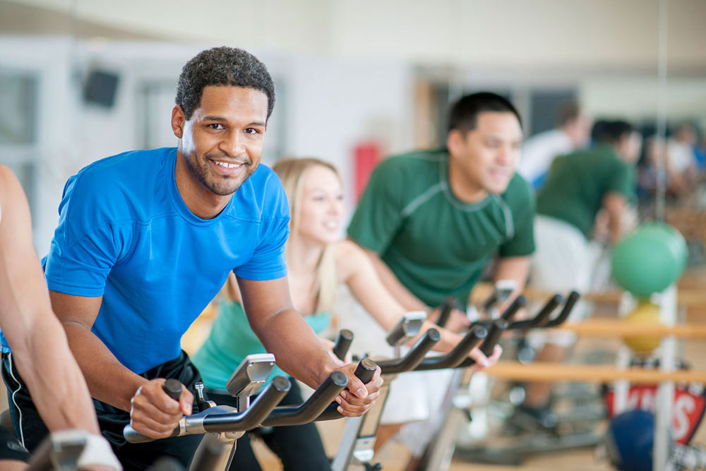 man smiling on an exercise bike in workout class