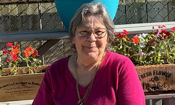 Liver cancer patient Brenda posed outside a flower garden