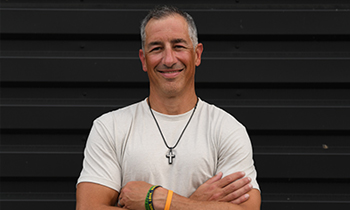 Pancreatic cancer patient, Dusty, standing with arms crossed