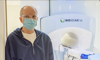 Prostate cancer patient, John, posing in front of radiation machine