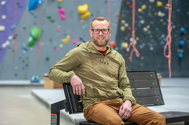 vascular surgery patient Eric posed in front of a climbing gym wall