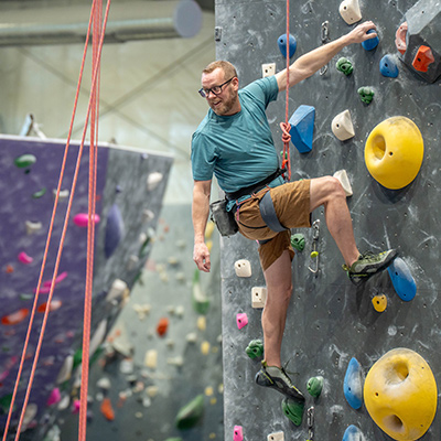Eric climbing up a rock wall at the climbing gym