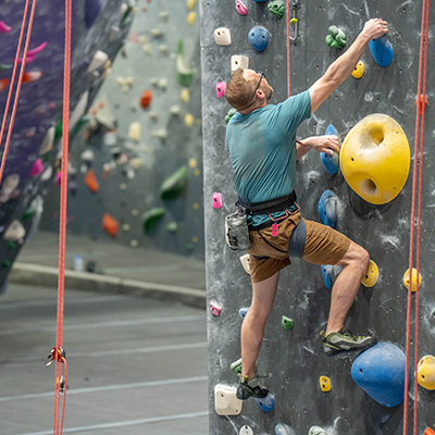 Eric climbing up a rock wall at the climbing gym