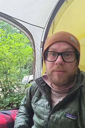 Eric sitting inside a tent while camping outdoors